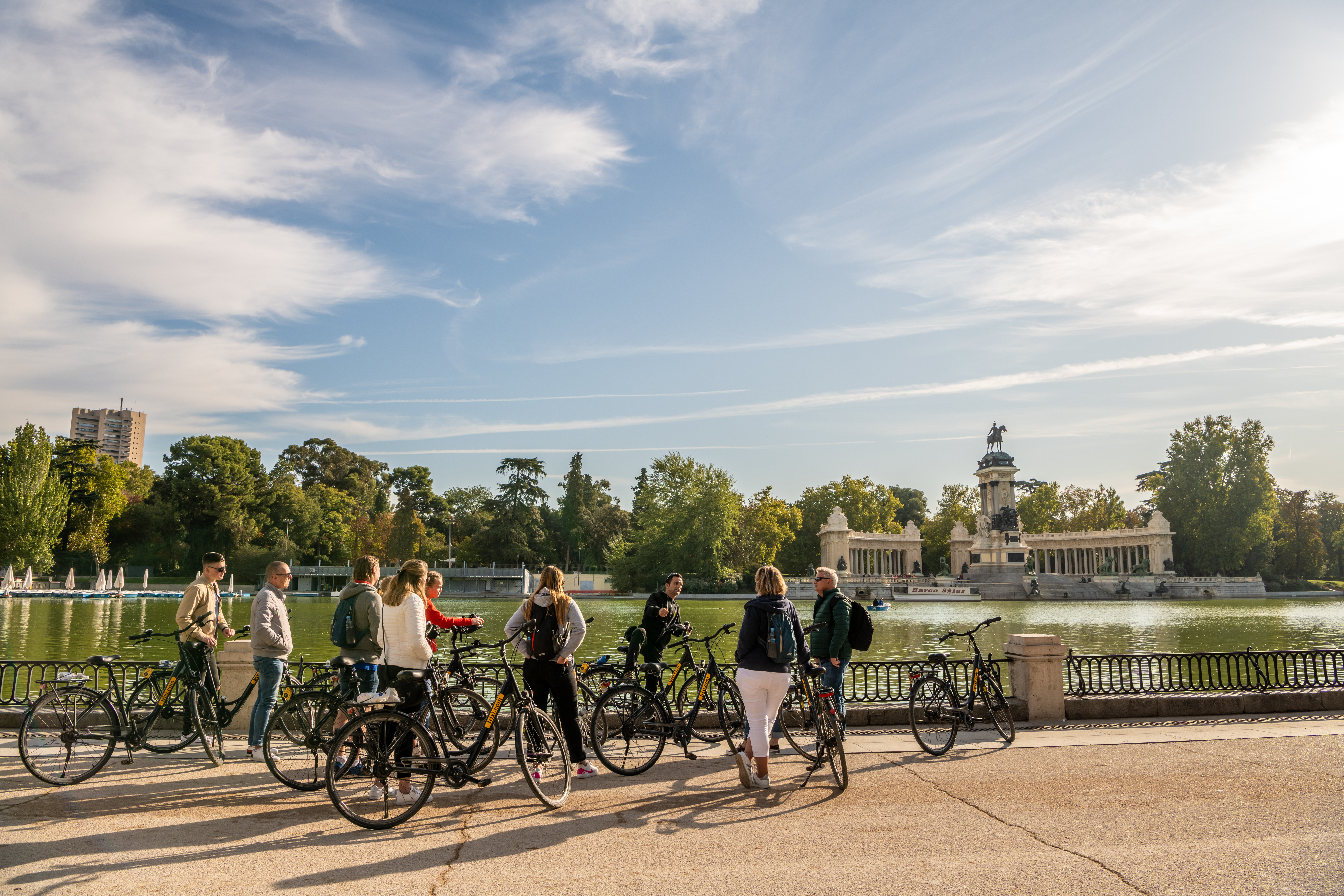 People begin a guided bicycle tour amidst the beautiful scenery in El Retiro Park, a popular and scenic park in central Madrid.